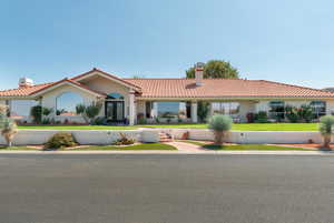 View of front of house with a chimney, a tiled roof, a front lawn, stucco siding, and french doors