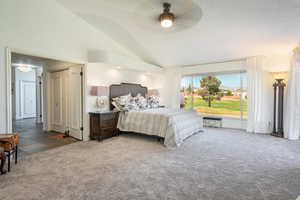 Carpeted bedroom with vaulted ceiling and ceiling fan