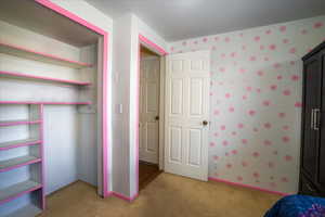 Unfurnished bedroom featuring light carpet and a closet