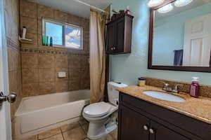 Full bath featuring light tile patterned floors, vanity, shower / bath combo with shower curtain, and a textured wall