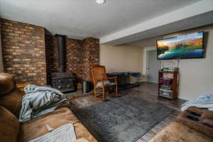 Living area featuring wood finished floors, a wood stove, and a textured ceiling