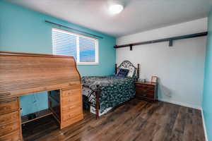 Bedroom featuring dark wood-style floors and baseboards