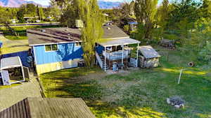 Rear view of property with stairs, a deck with mountain view, a yard, and a storage unit