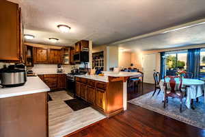 Kitchen featuring light countertops, appliances with stainless steel finishes, light wood-type flooring, decorative backsplash, and a textured ceiling