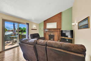 Living room featuring a brick fireplace, vaulted ceiling, and fireplace.