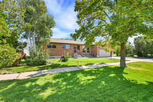 Ranch-style home with brick siding, driveway, a front yard, and an attached garage
