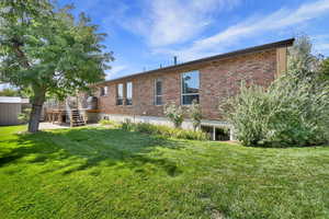 Back of house with brick,  lawn and a deck