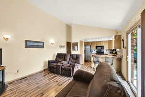 Living area with wood-style flooring, high vaulted ceiling and a fireplace