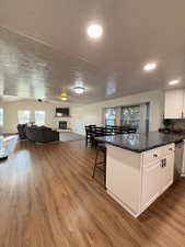 Kitchen with a peninsula, a textured ceiling, a breakfast bar area, white cabinets, and open floor plan