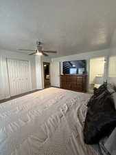 Bedroom featuring a closet, ceiling fan, a textured ceiling, and carpet flooring