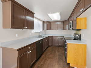 Kitchen with stainless steel appliances, light countertops, dark wood-style floors, and dark brown cabinets