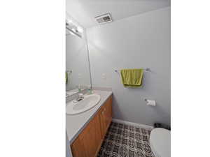 Half bathroom featuring vanity and dark tile patterned flooring