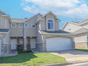 Traditional-style home featuring a garage, stucco siding, concrete driveway, and a front yard