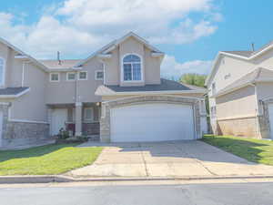 Traditional-style house with stucco siding, concrete driveway, a front lawn, and roof with shingles
