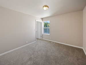 Empty room with carpet and a textured ceiling