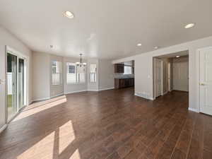 Unfurnished living room featuring a chandelier, recessed lighting, and dark wood finished floors