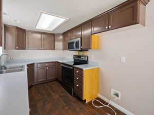 Kitchen with stainless steel appliances, light countertops, dark wood-type flooring, and dark brown cabinetry