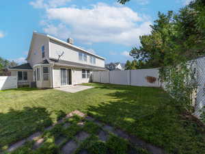 Rear view of property featuring a patio area, a fenced backyard, and a chimney