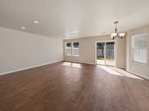 Unfurnished living room featuring dark wood-style flooring, a textured ceiling, recessed lighting, and a chandelier