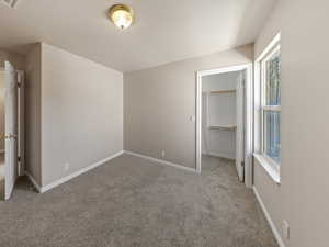 Unfurnished bedroom featuring a spacious closet and light colored carpet