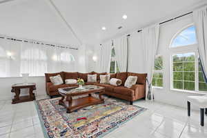 Living room with light tile patterned floors, high vaulted ceiling, and recessed lighting