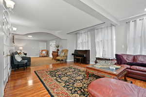 Living area with arched walkways, wood finished floors, and recessed lighting