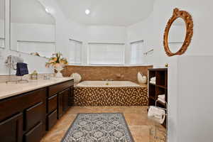 Bathroom with a garden tub, vanity, and light tile patterned flooring