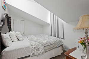 Bedroom with carpet floors and vaulted ceiling