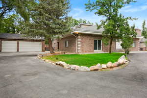 Mid-century inspired home featuring brick siding, a front yard, a shingled roof, and asphalt driveway
