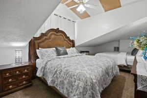 Bedroom with vaulted ceiling, dark carpet, a textured ceiling, and ceiling fan