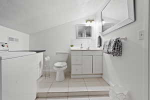 Bathroom with washer / dryer, vanity, a textured ceiling, decorative backsplash, and light tile patterned floors