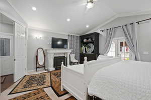 Bedroom featuring a glass covered fireplace, a ceiling fan, lofted ceiling, recessed lighting, and ornamental molding