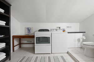 Washroom with light tile patterned floors, a textured ceiling, and washer and clothes dryer