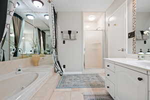 Bathroom featuring a shower stall, vanity, a garden tub, and light tile patterned flooring