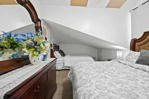 Bedroom featuring vaulted ceiling and dark carpet
