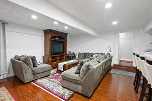 Living area with a textured ceiling, recessed lighting, and dark wood finished floors