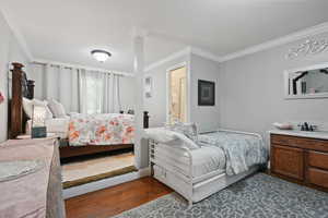 Bedroom with ornamental molding and dark wood-style flooring