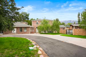 View of front facade featuring a front yard, brick siding, a mountain view, asphalt driveway, and a shingled roof