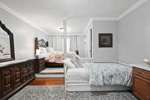 Bedroom with ornamental molding and dark wood finished floors