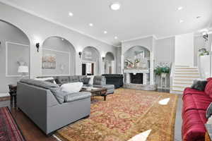 Living area featuring wood finished floors, ornamental molding, a fireplace with raised hearth, and recessed lighting