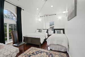 Bedroom with dark wood finished floors, vaulted ceiling, and recessed lighting