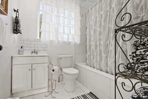 Full bathroom featuring light tile patterned flooring, tiled shower / bath, vanity, and backsplash