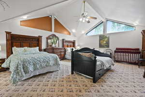 Bedroom with high vaulted ceiling, light colored carpet, beamed ceiling, and a ceiling fan