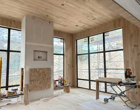 Construction update: View of living with two way fireplace and wood floors, walls and ceiling.