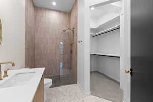 Full bathroom with vanity, tiled shower, light tile patterned floors, recessed lighting, and a walk in closet