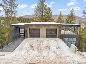 Snow covered garage featuring a mountain view and driveway