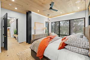 Bedroom with light wood-type flooring, wooden ceiling, ceiling fan, and suspended lighting