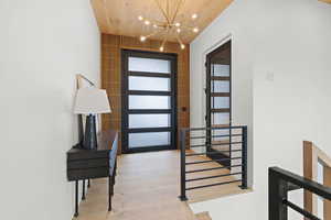 Foyer entrance featuring a chandelier, wood ceiling, and light wood-style floors