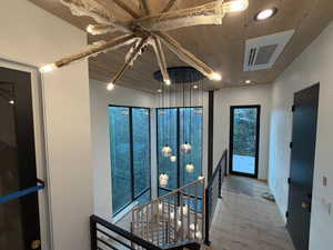 Hall with an upstairs landing, wood ceiling, recessed lighting, elevator and wood finished floors