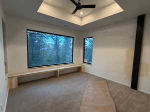 Carpeted empty room featuring a raised ceiling, a ceiling fan, and recessed lighting